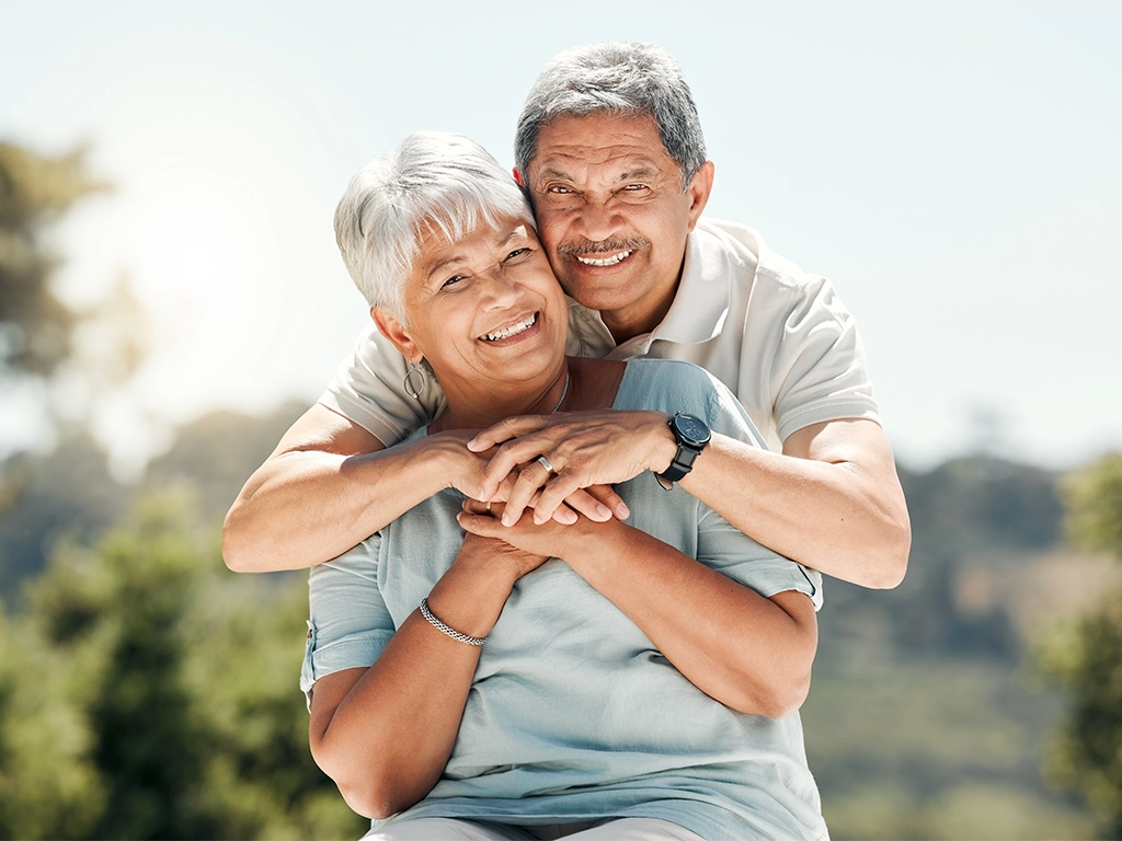senior couple smiling and hugging outdoors enjoying time together senior couple smiling and hugging outdoors enjoying time together